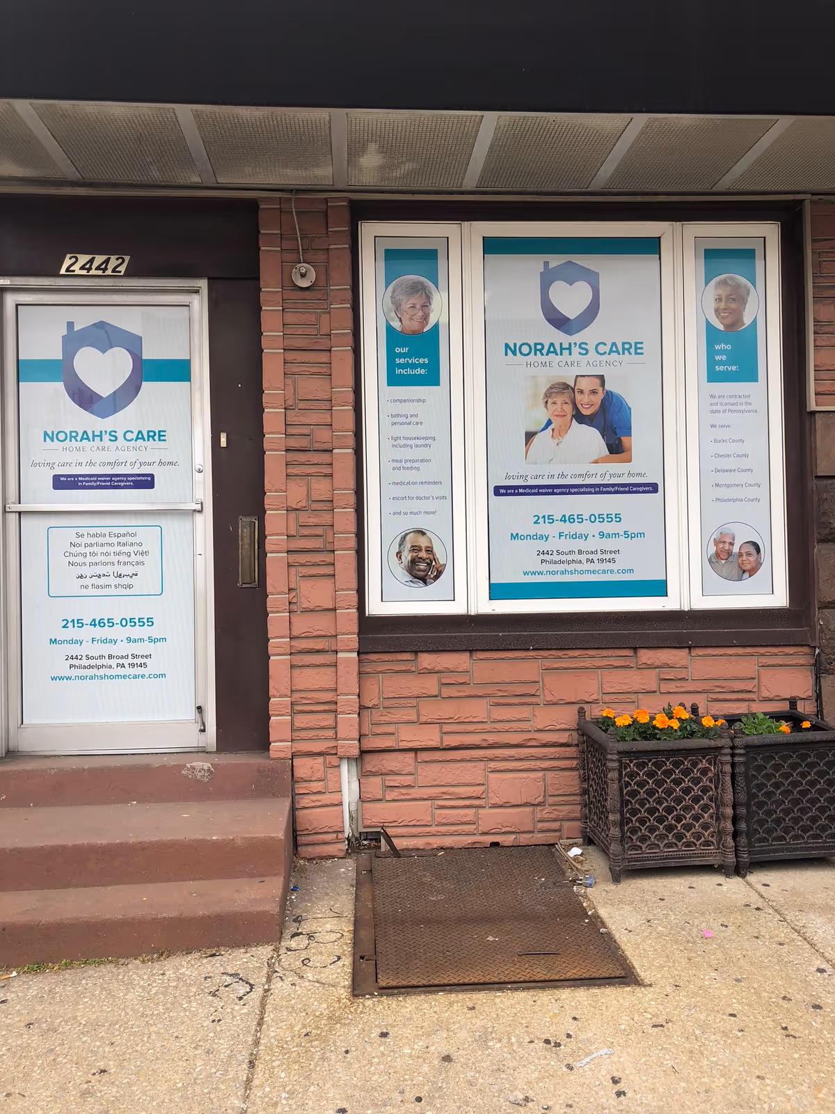Exterior view of NORAH'S CARE storefront with window ads and brick facade.