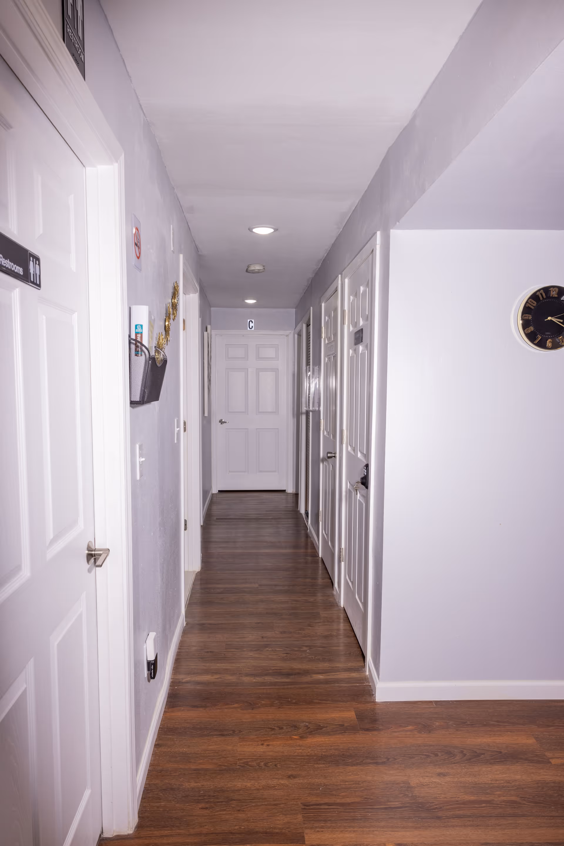 Long hallway inside a senior living facility with closed doors and wood flooring.