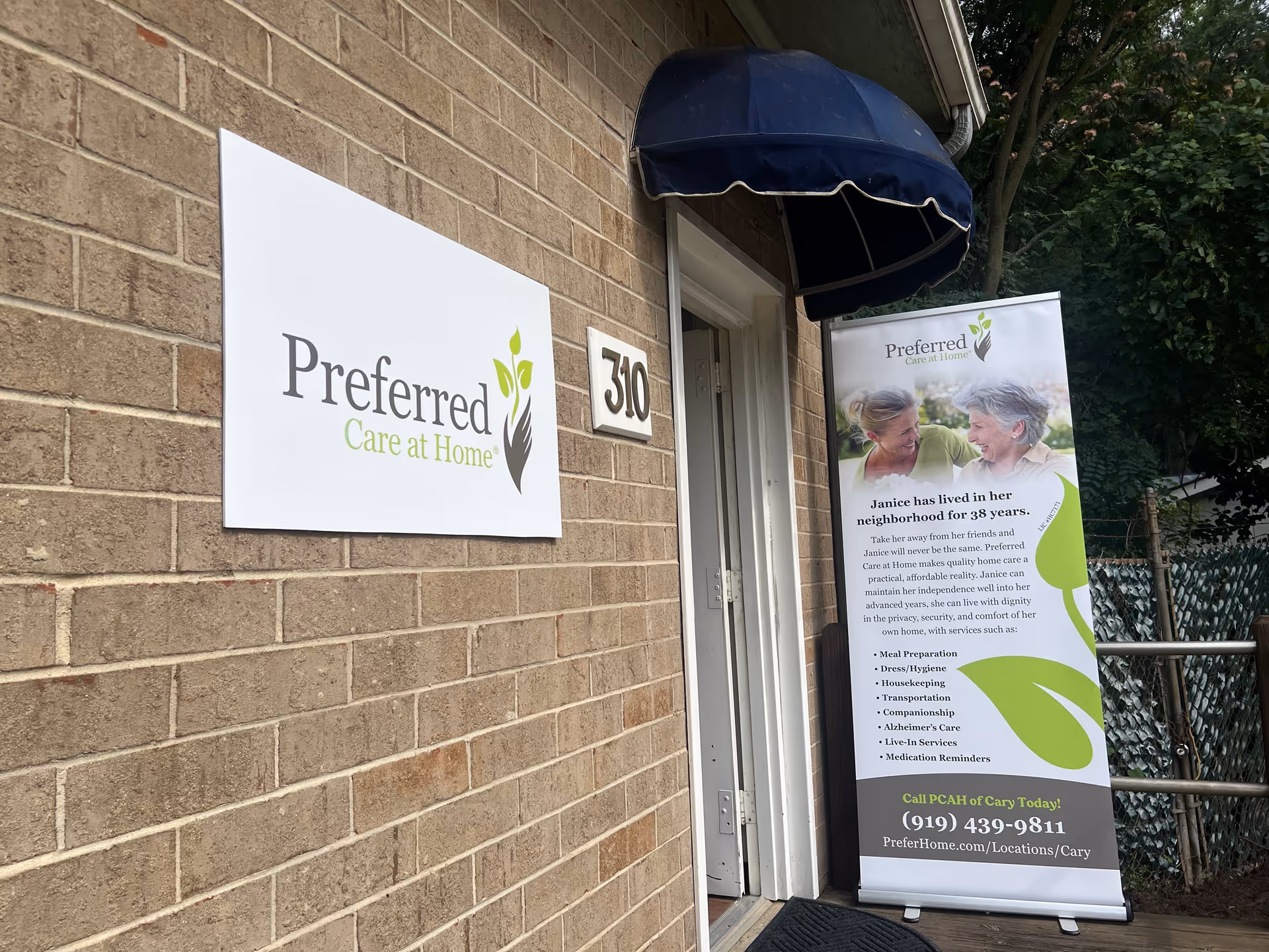 Exterior view of a brick facility entrance with a Preferred Care at Home sign and banner.