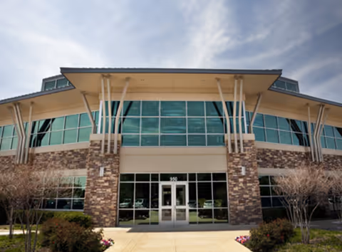 Front view of Hello! Home Care senior living facility with glass windows and stone facade.