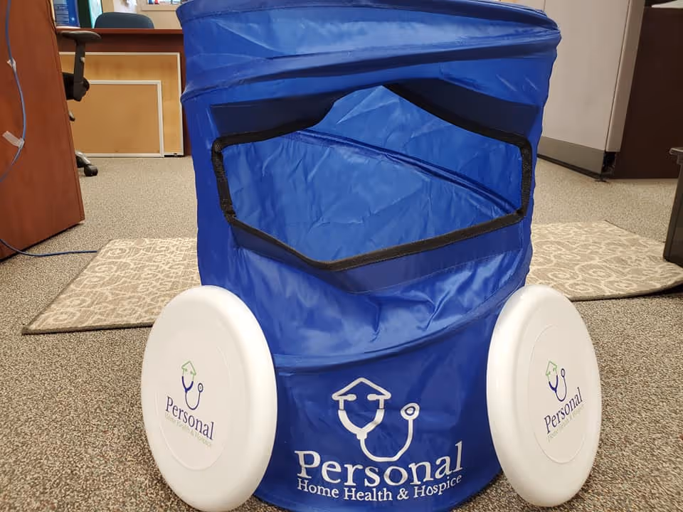 Blue wheeled medical device with Personal logo sits on carpeted interior floor.