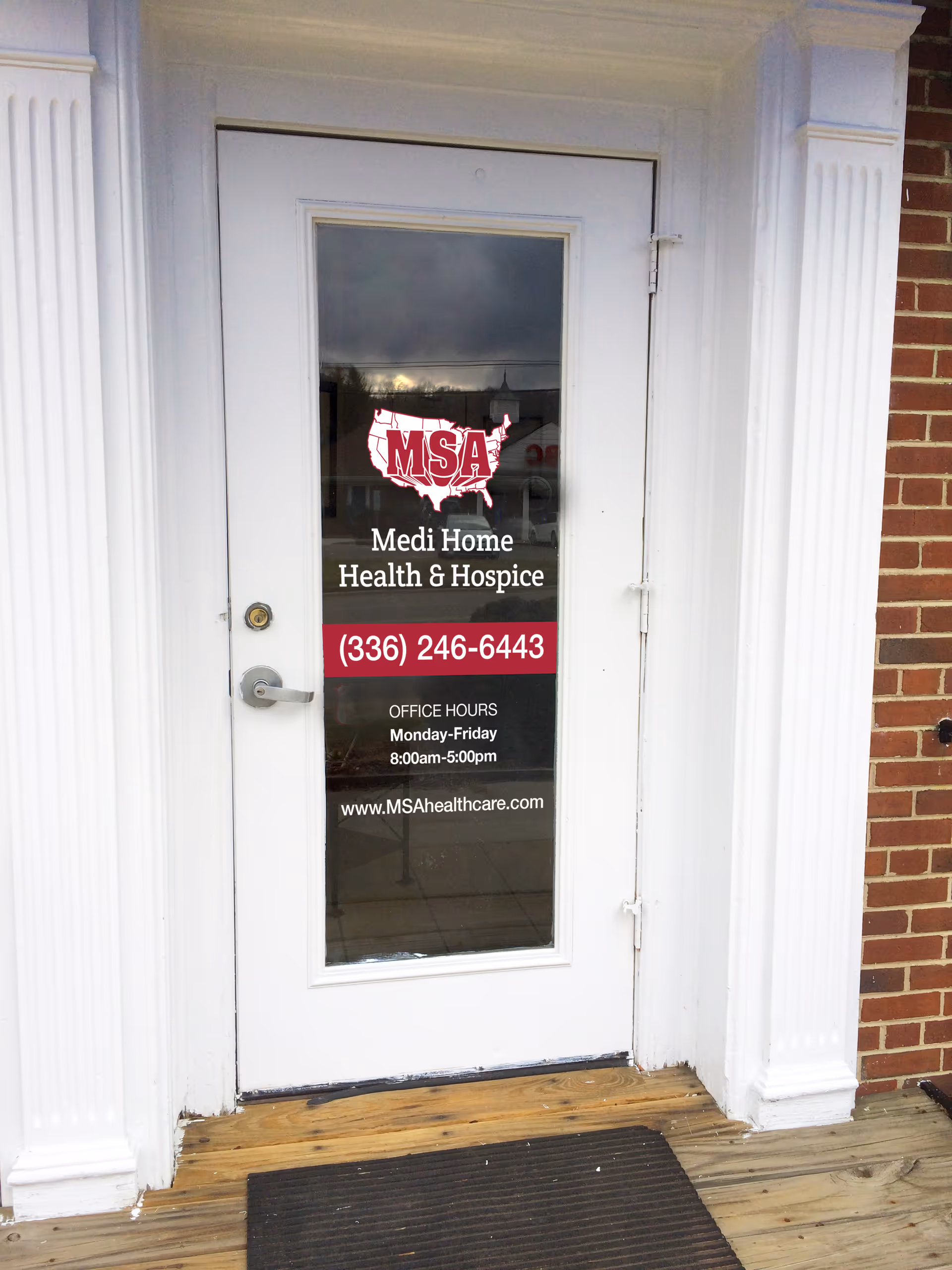 White entrance door with Medi Home Health & Hospice sign on brick exterior.