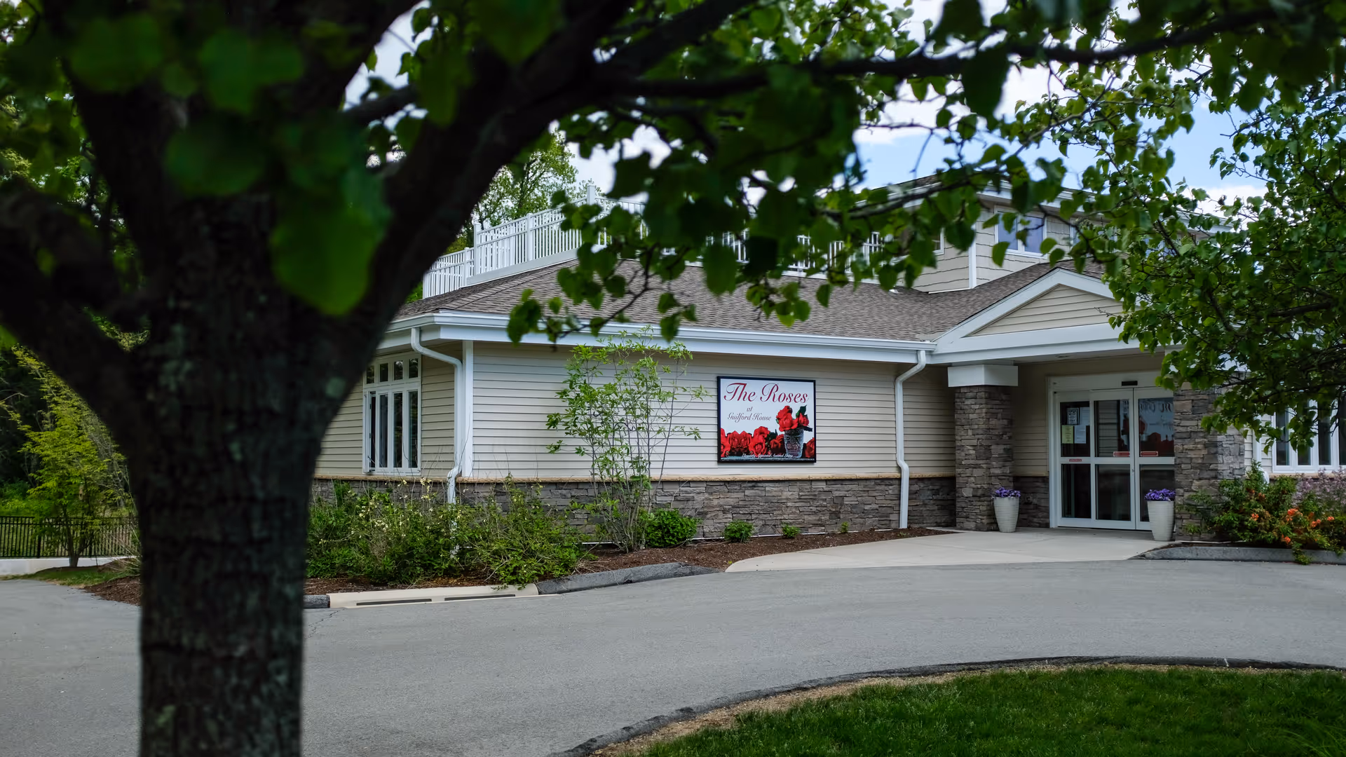 Front exterior of a senior living facility with a sign and glass entrance.