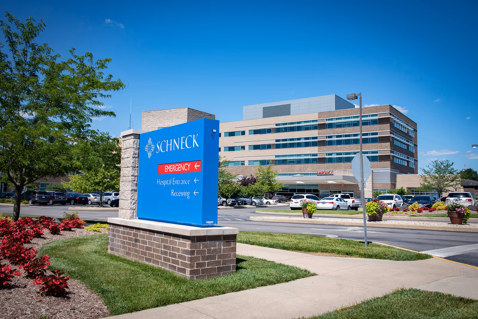 Blue Schneck Medical Center Home Health sign in foreground with campus and parked cars