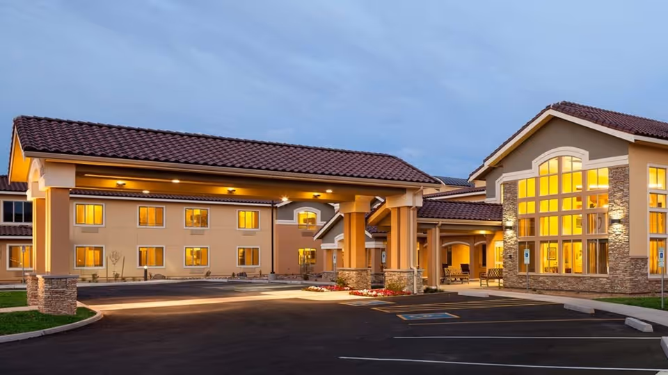 Exterior view of Farmington Station Senior Living with illuminated entrance and large front windows.