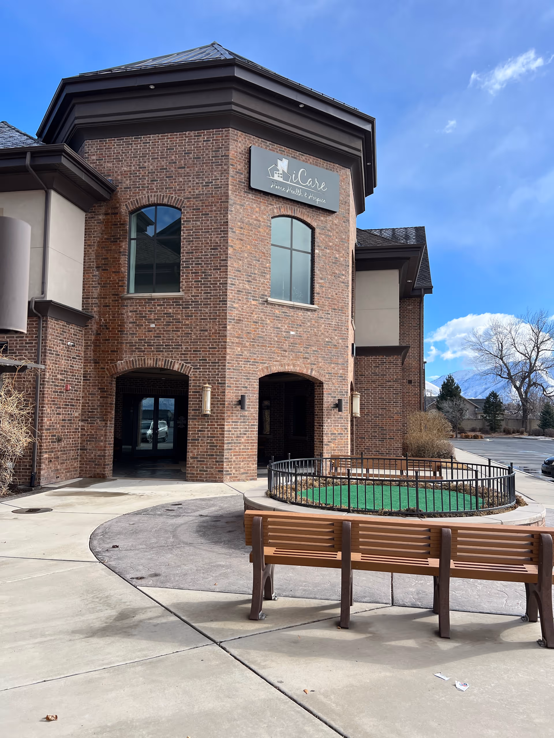 Brick exterior of iCare Home Health & Hospice with a bench and circular courtyard.