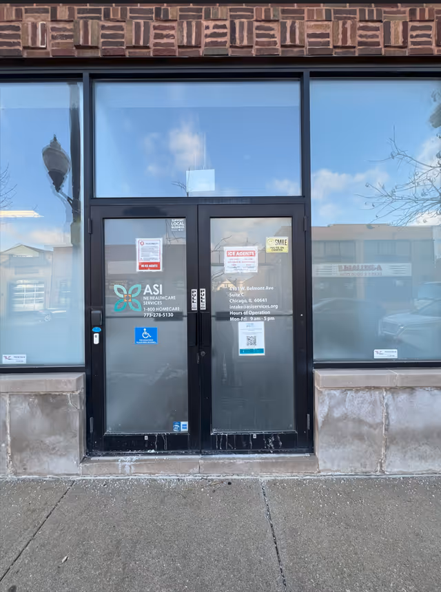 Front entrance of ASI Services building with glass doors, signs, and wheelchair accessibility symbol.