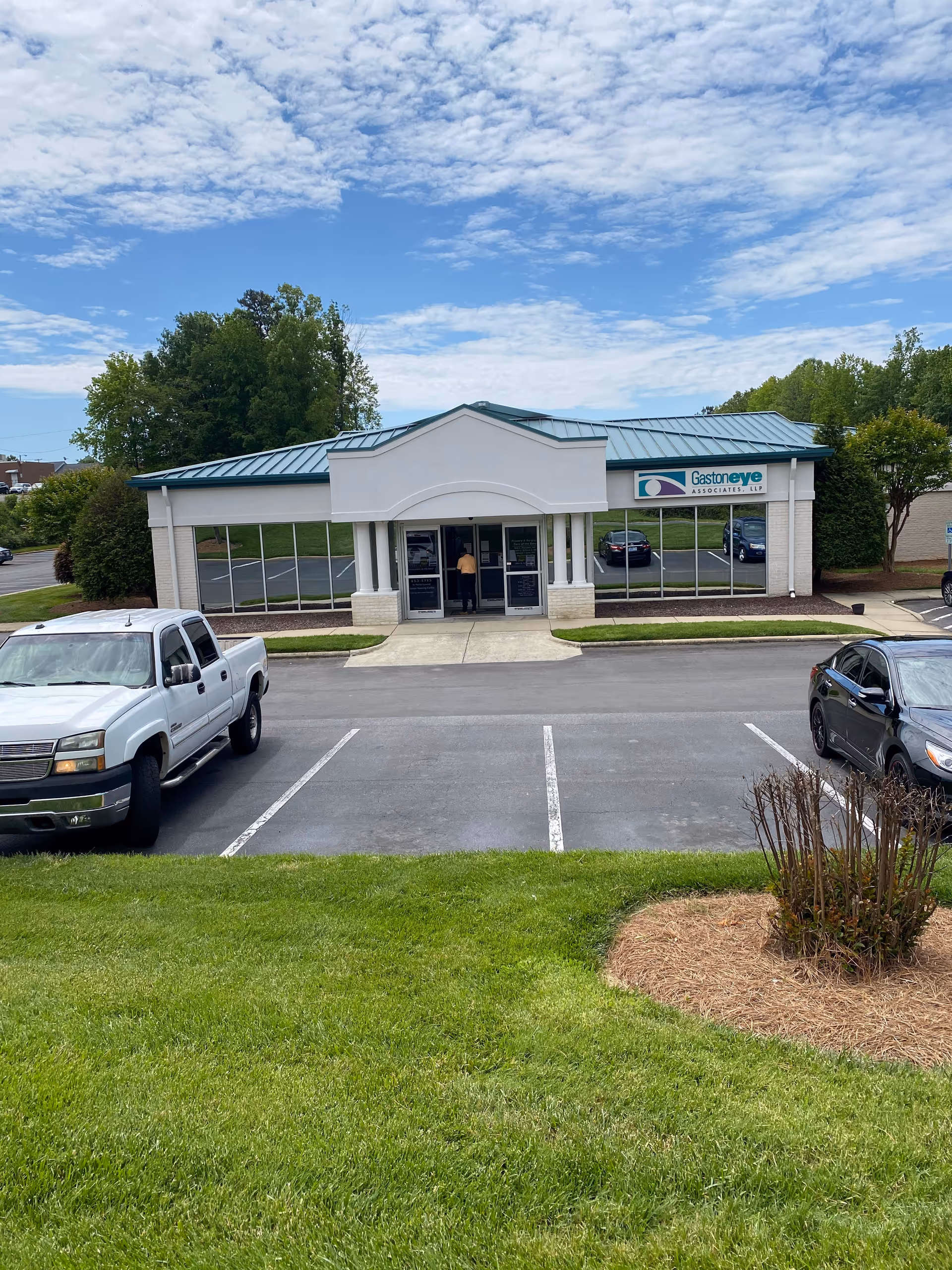 Front view of a single-story building with glass windows and a parking lot.