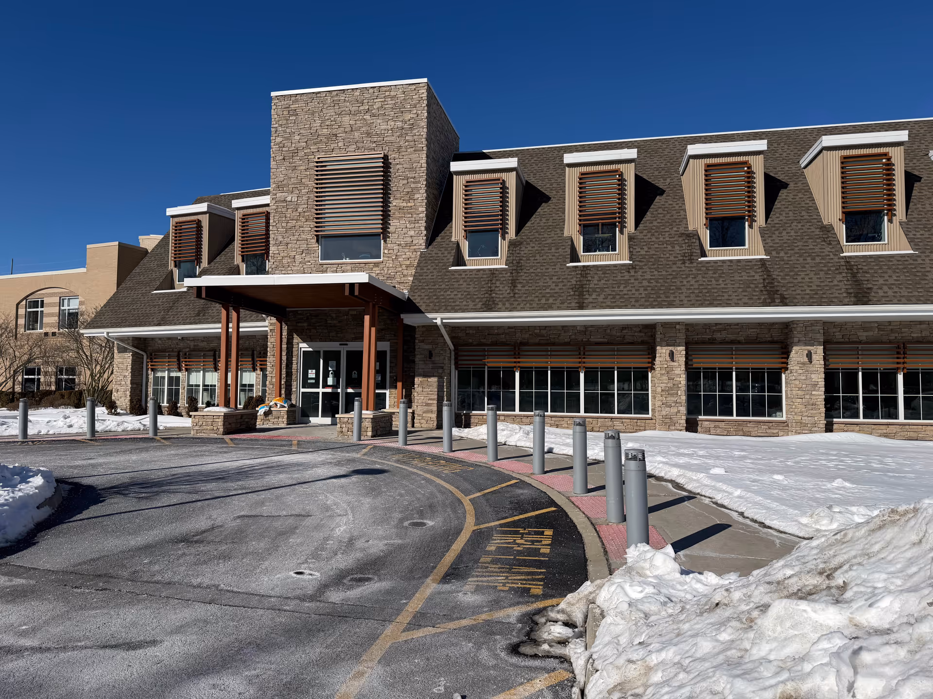 Exterior view of a modern senior living facility with a snow-covered driveway.