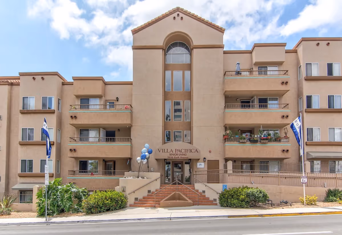 Front view of Villa Pacifica senior living building with steps, entrance, and balconies.