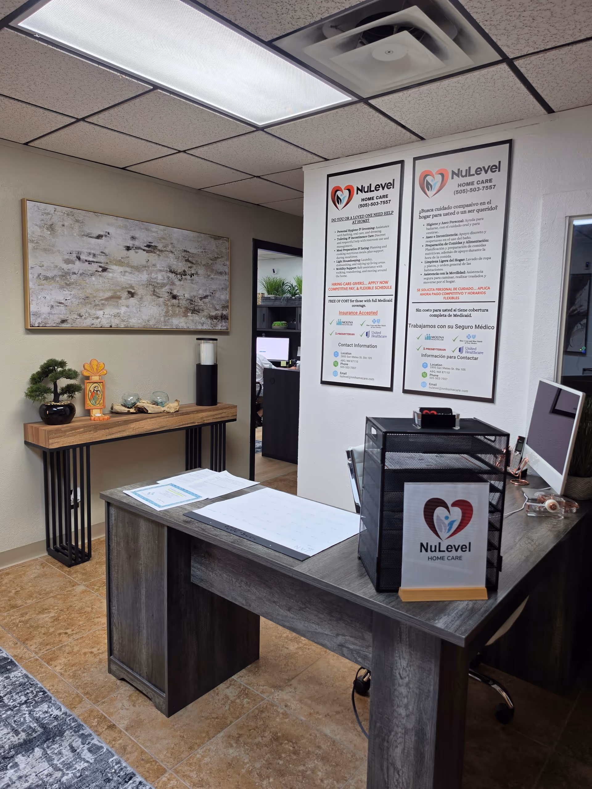Reception desk area with NuLevel Home Care signage, posters, and decor in an office.
