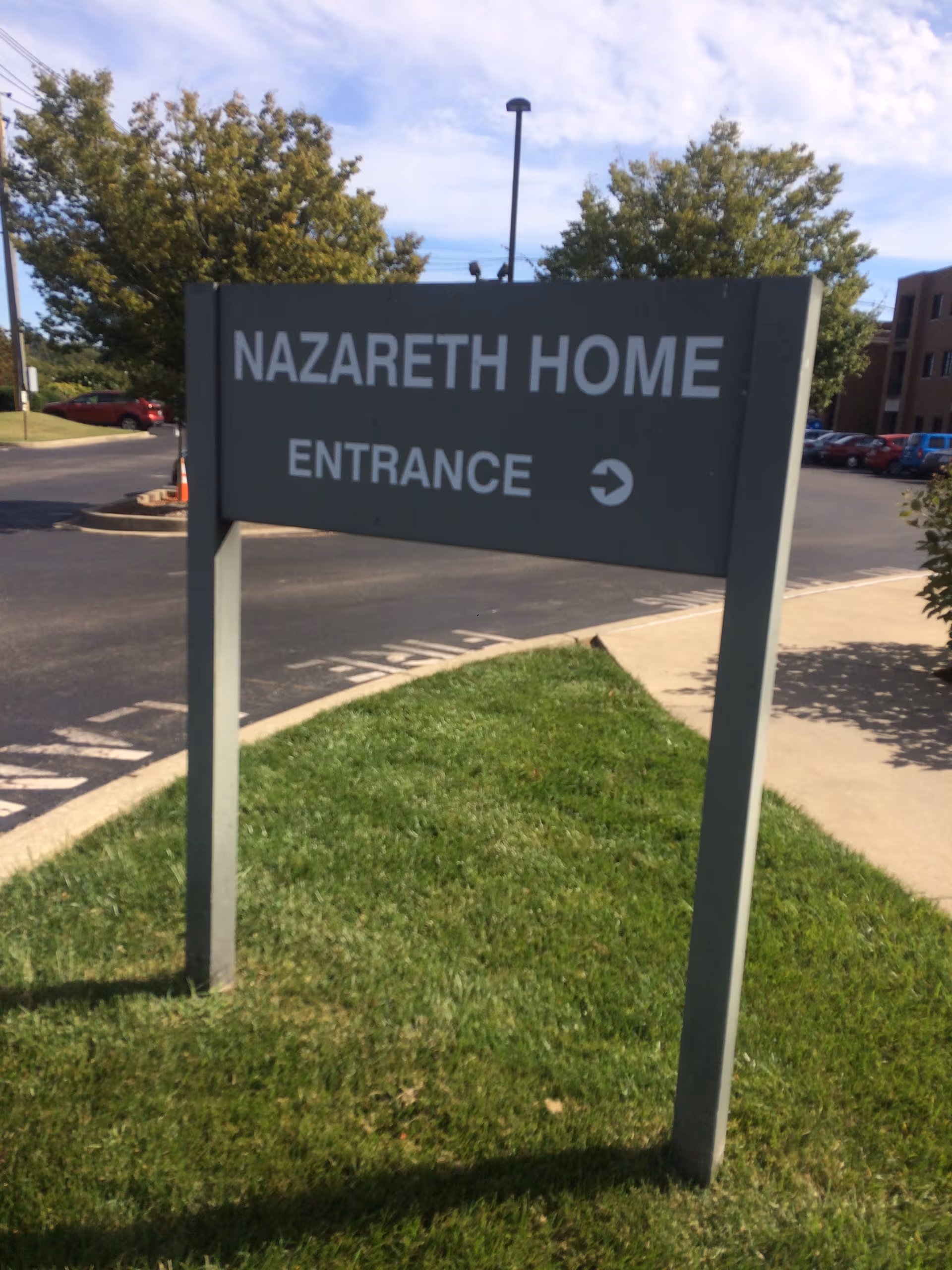 Nazareth Home Entrance sign on a grassy median by a parking lot