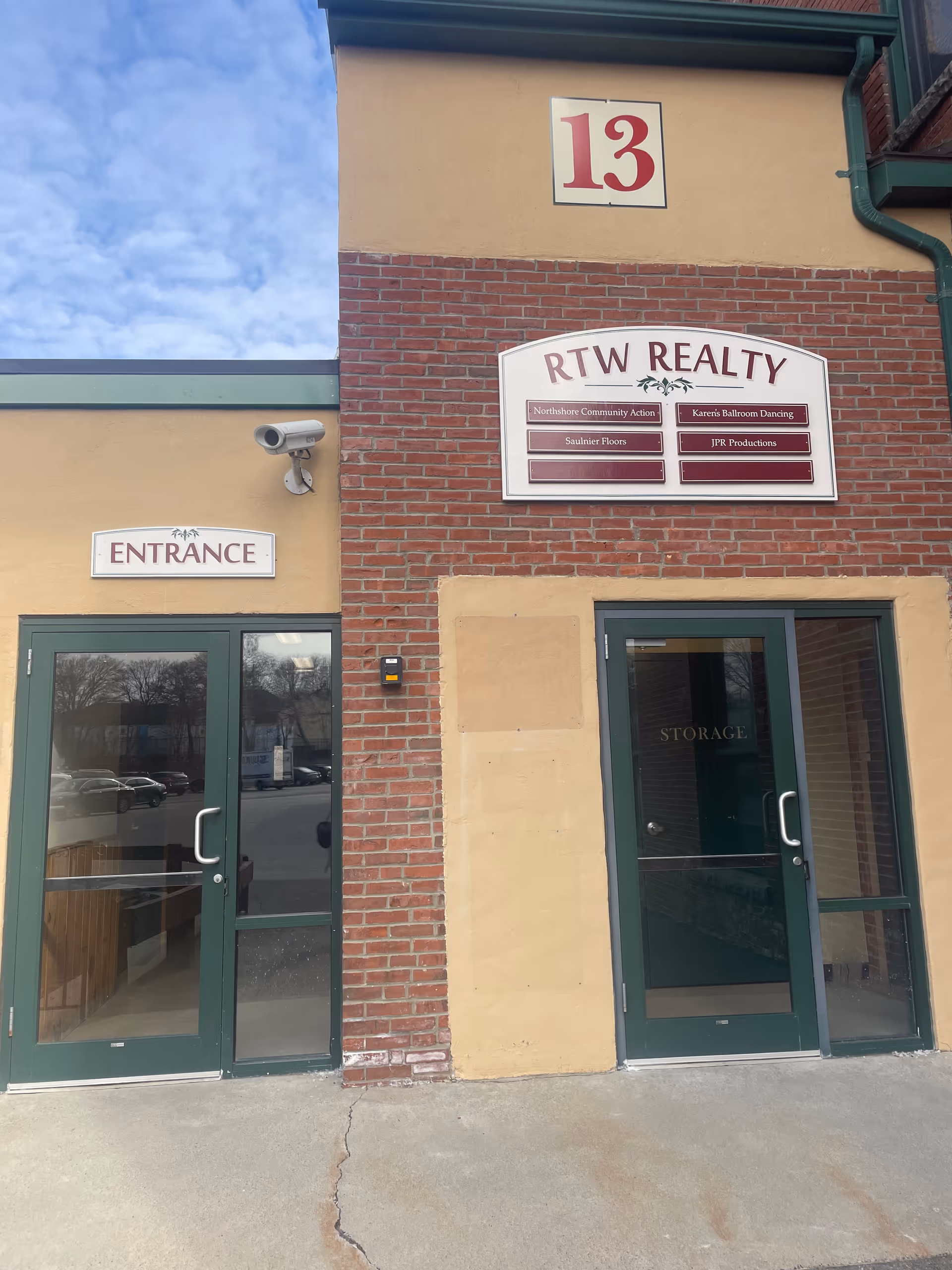 Brick building exterior with two green doors and an entrance sign.