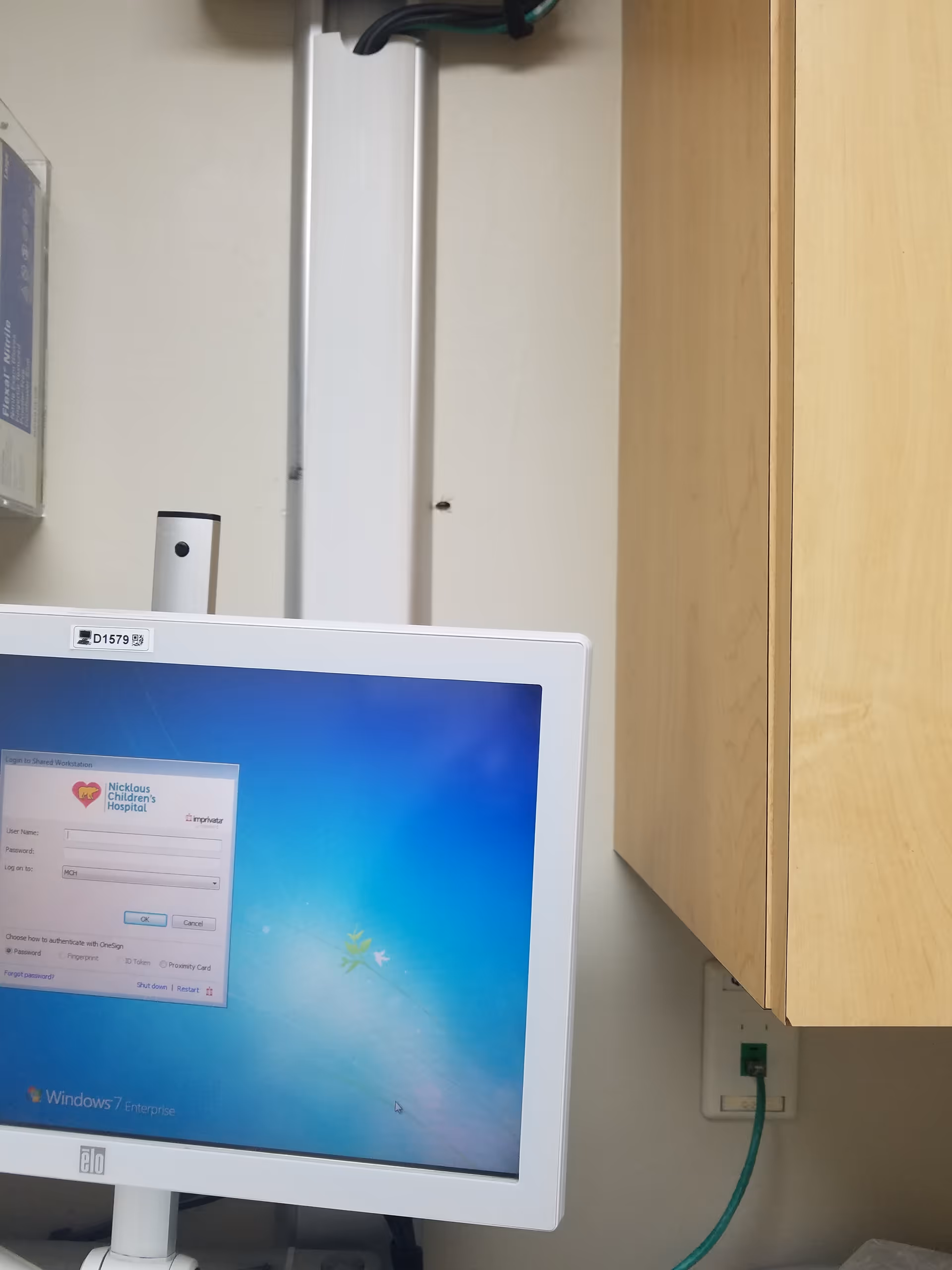 Computer monitor on a desk displaying a Windows login screen in a clinic office.