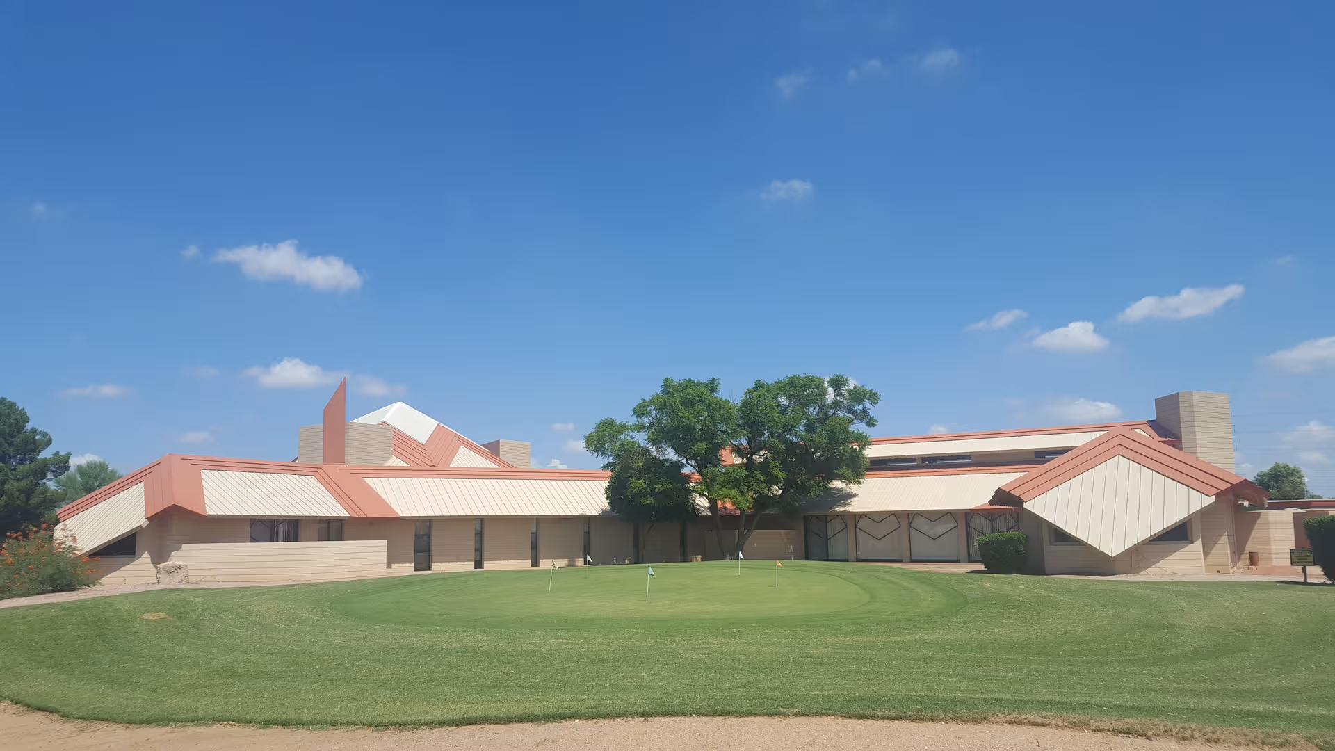 Exterior of Paradise Peak West senior living facility with beige walls, red roof accents, and lawn.
