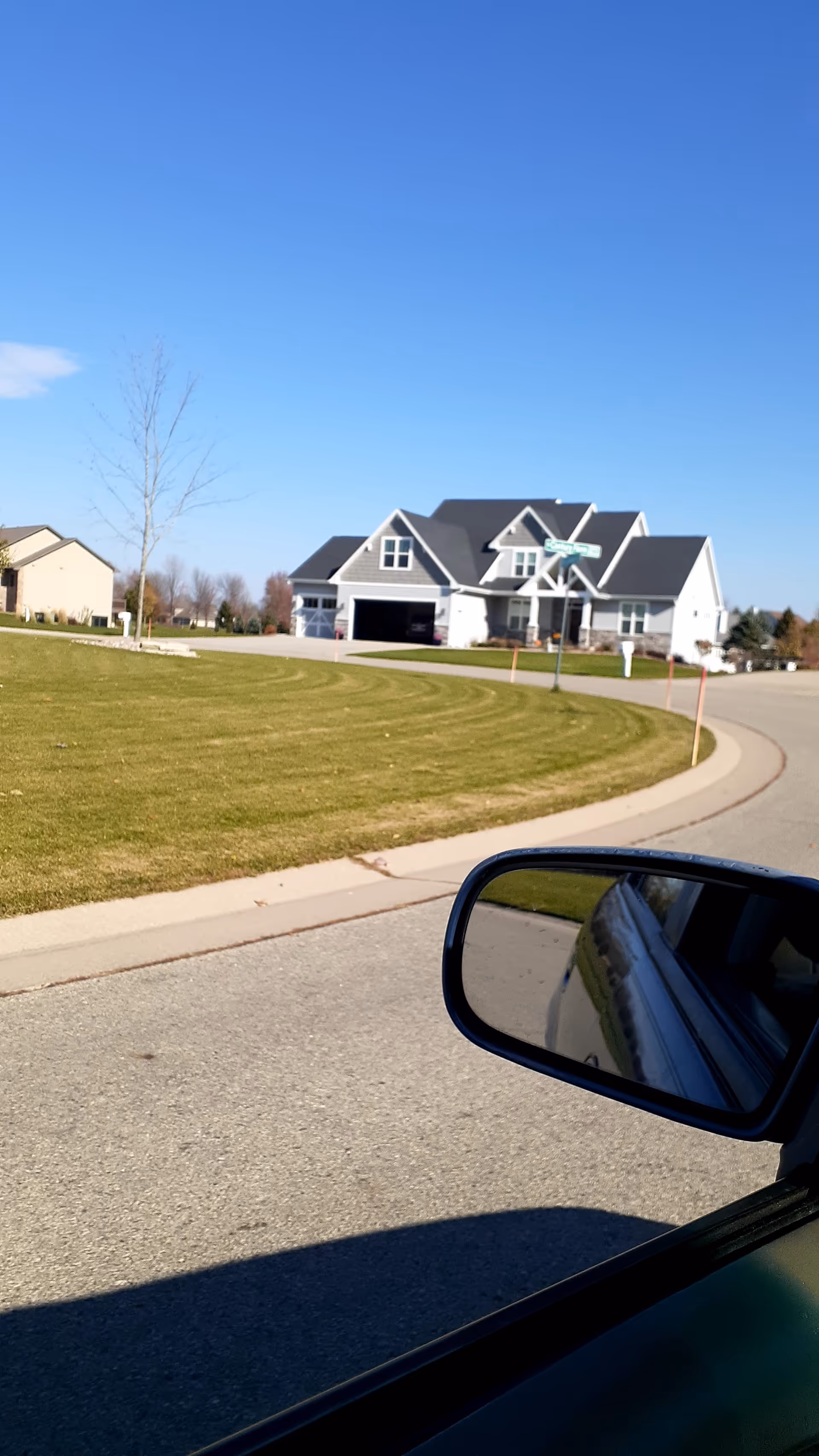 Sunny day exterior view of a modern senior living building with a curved driveway and car
