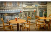 Senior living dining room with round tables, chairs, and a Paris storefront mural on the wall.