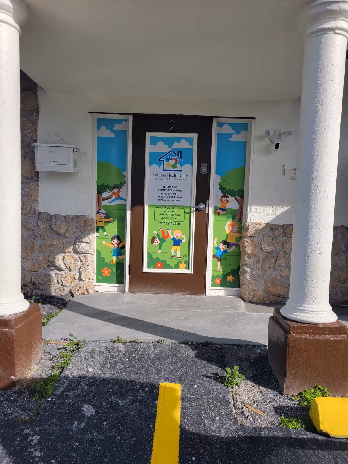 Front entrance of Palomo Health Care with colorful door panels, stone walls, and columns.
