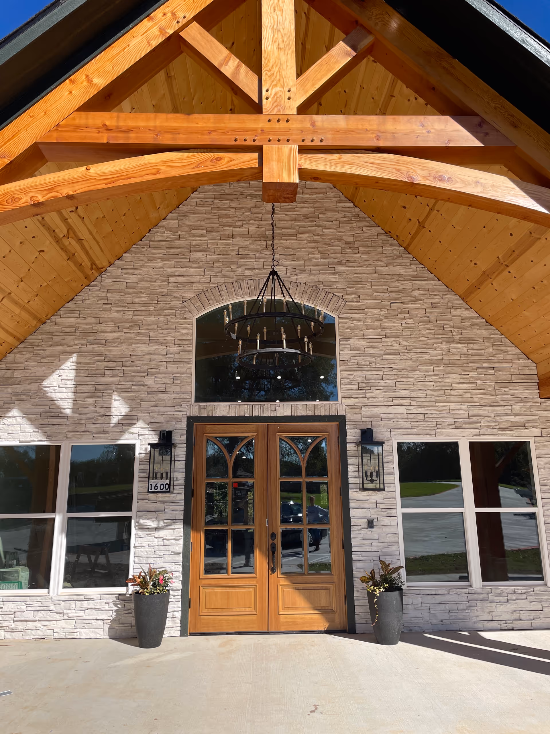 Stone-clad building entrance with wooden double doors and large overhead wooden beams.