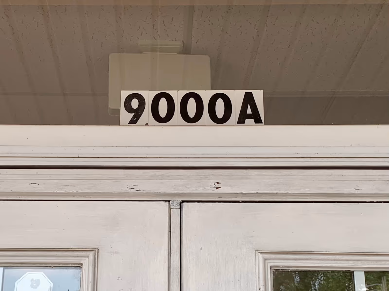 Close-up of a white door with a bold '9000A' sign above it.