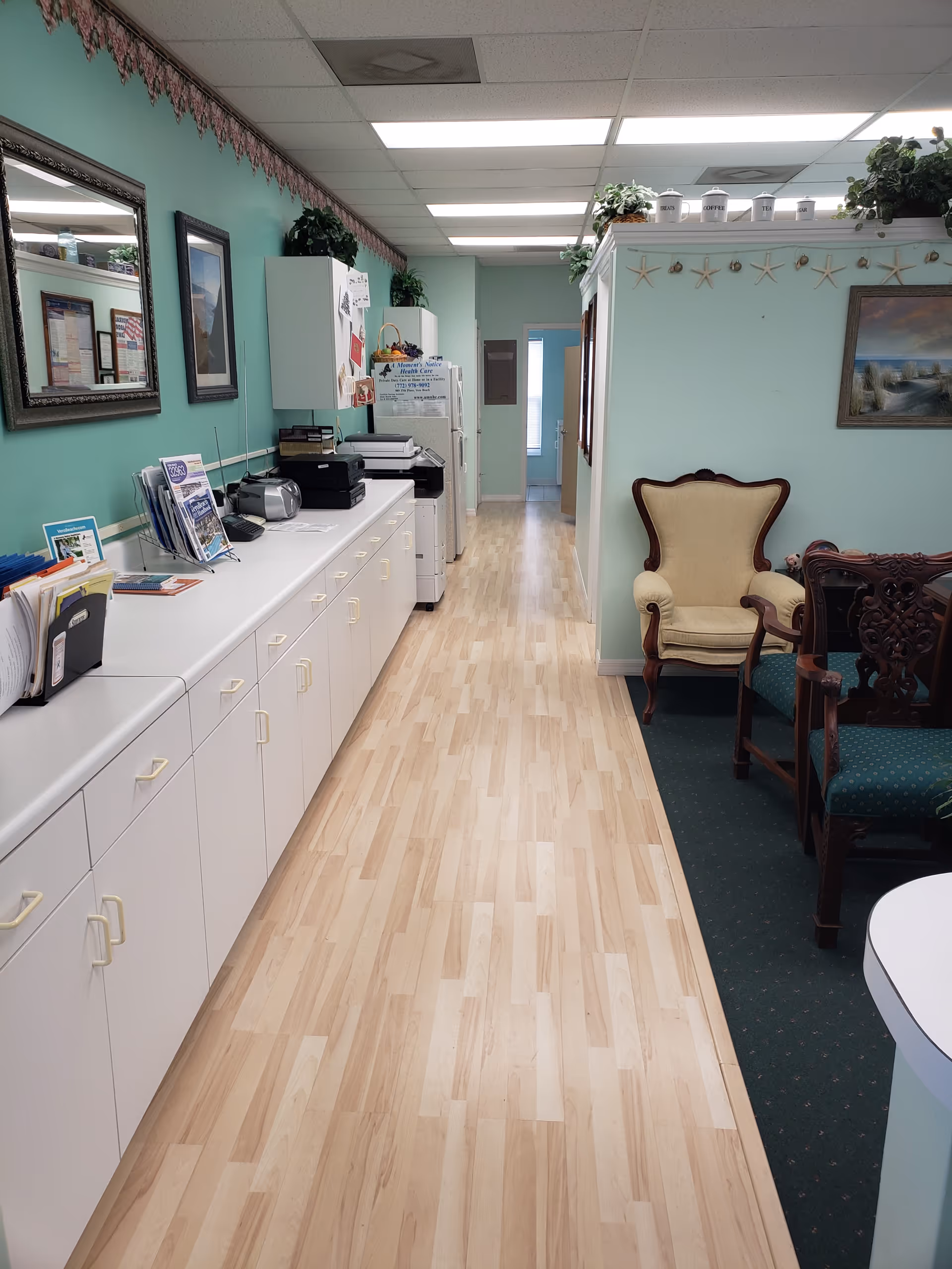 Bright interior corridor with white cabinets, office equipment, and seating.