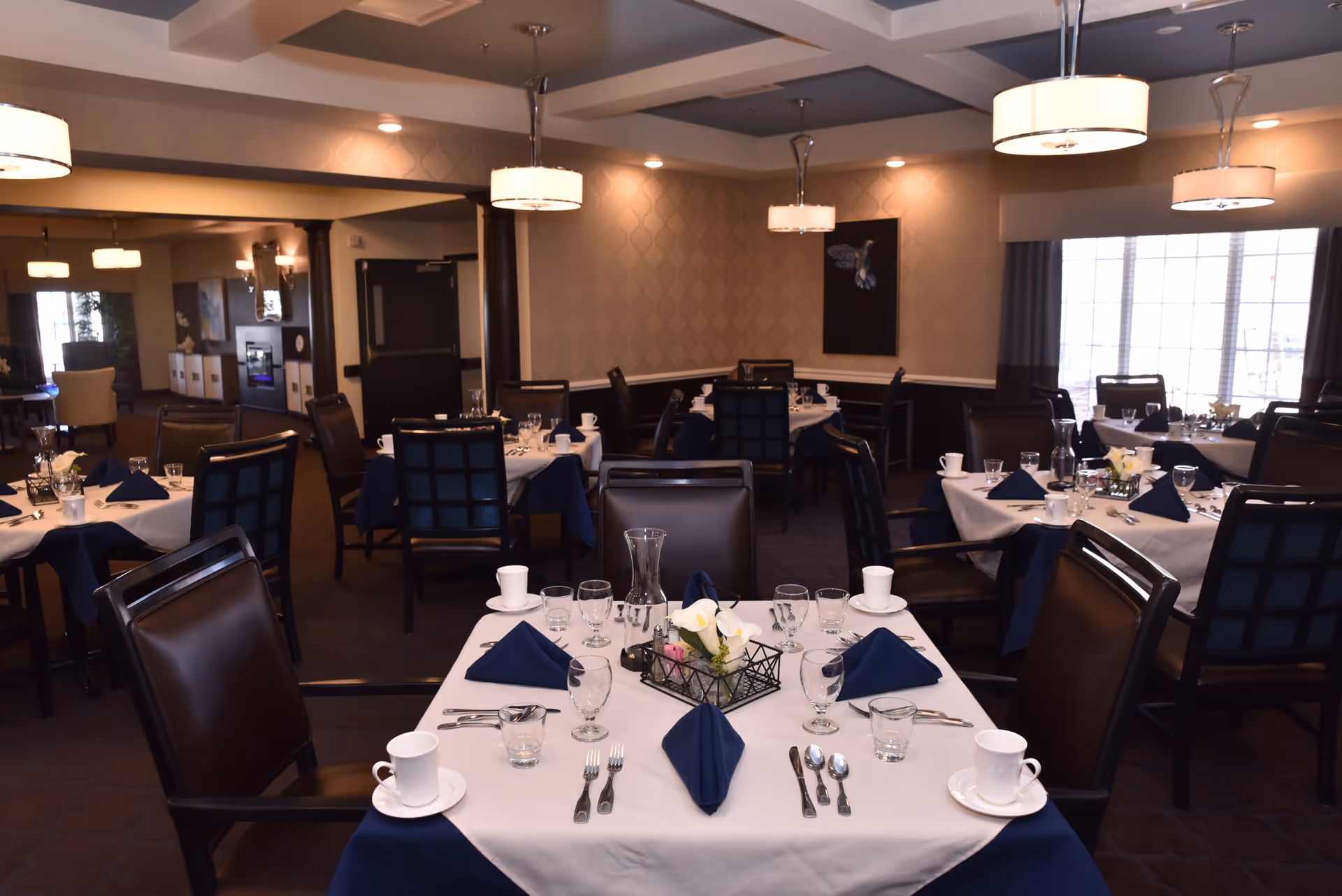 A dining area set with tables and dishes in a senior living facility.