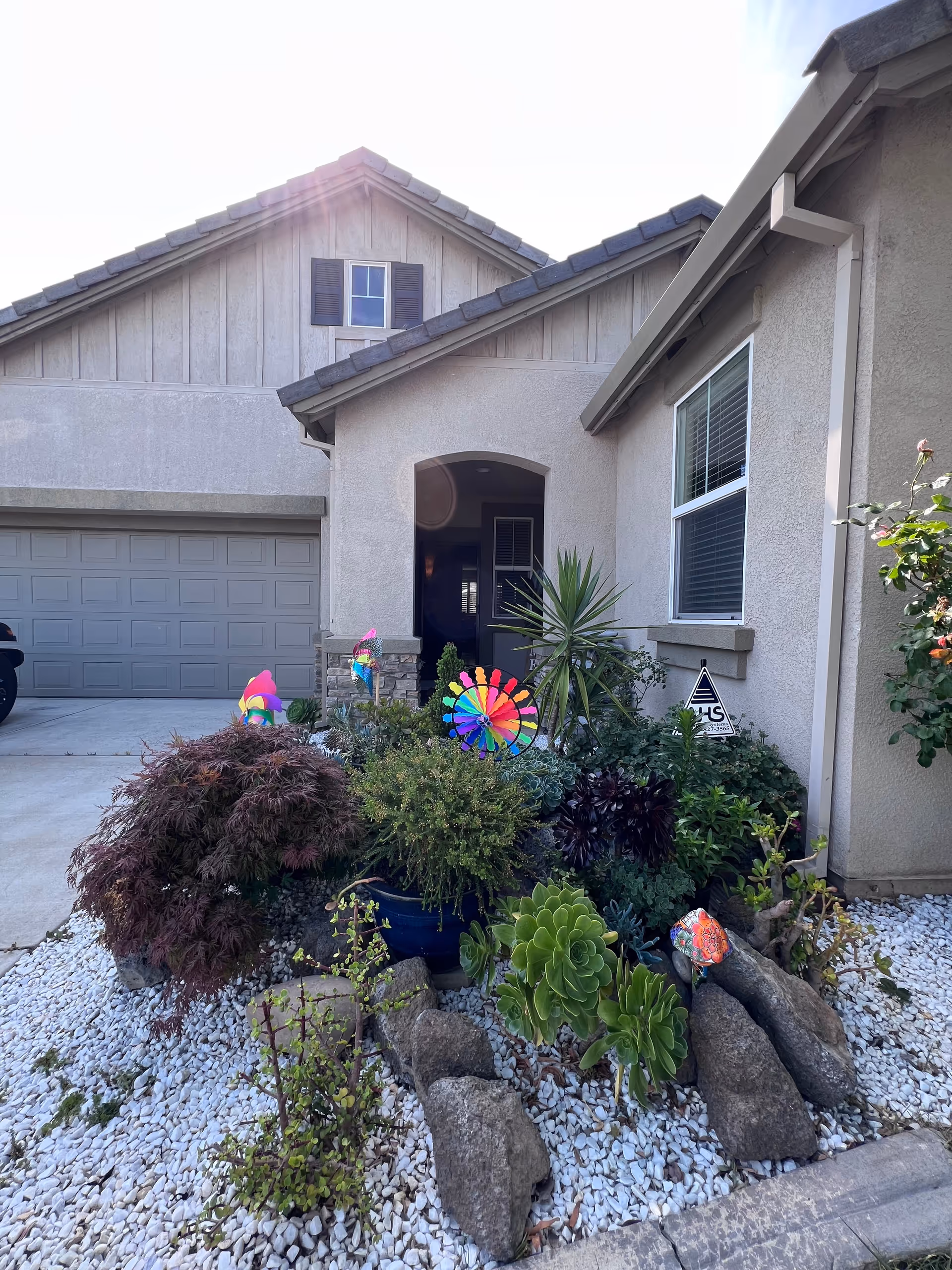 Front entrance of a beige house-style building with a landscaped rock garden and succulents.