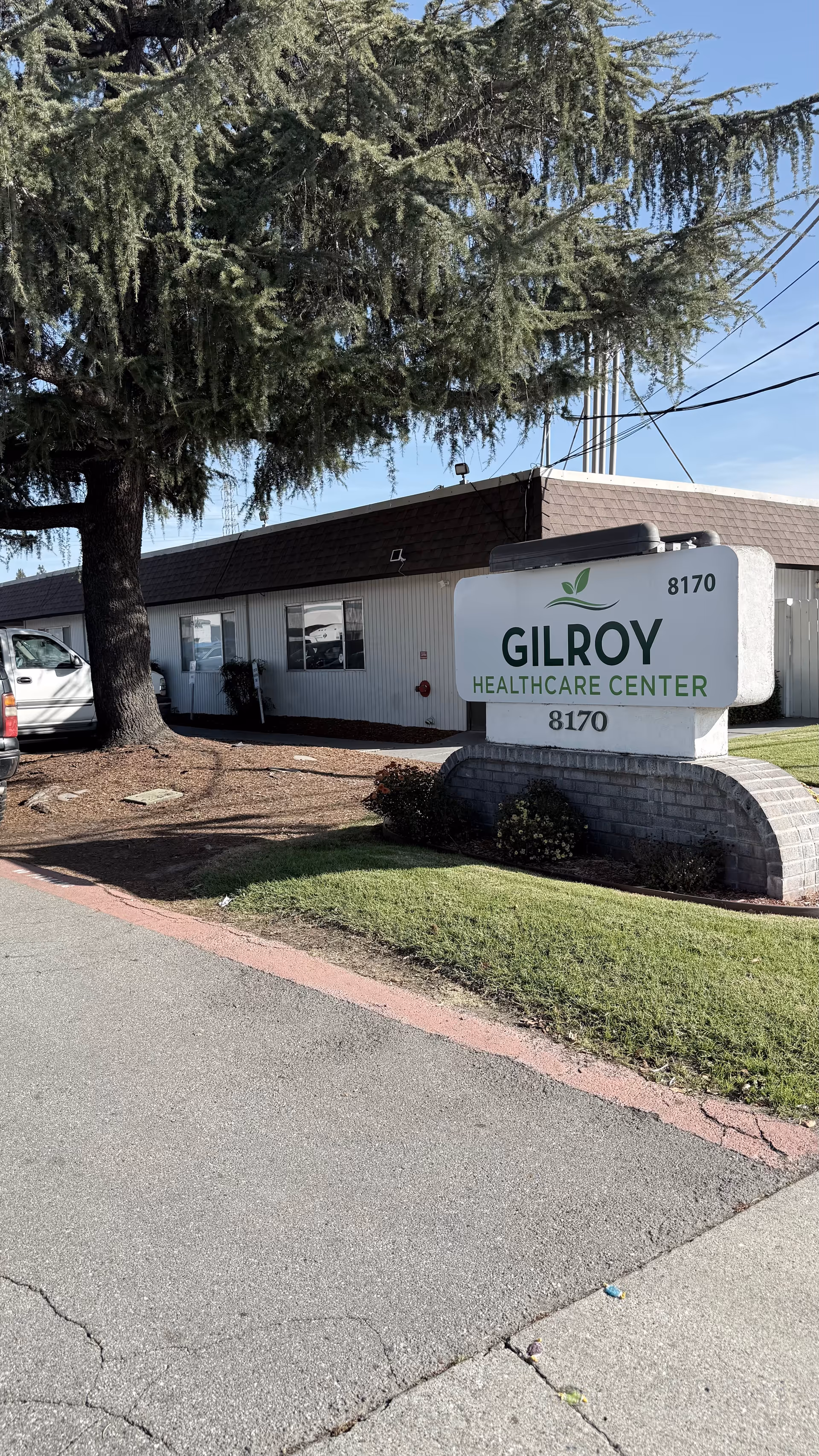 Exterior view of Gilroy Healthcare Center with sign and front entrance.