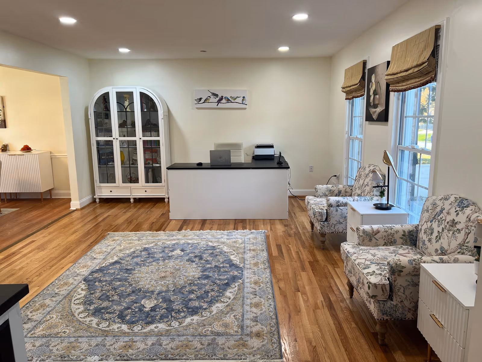 Bright lobby with reception desk, glass cabinet, and floral chairs.