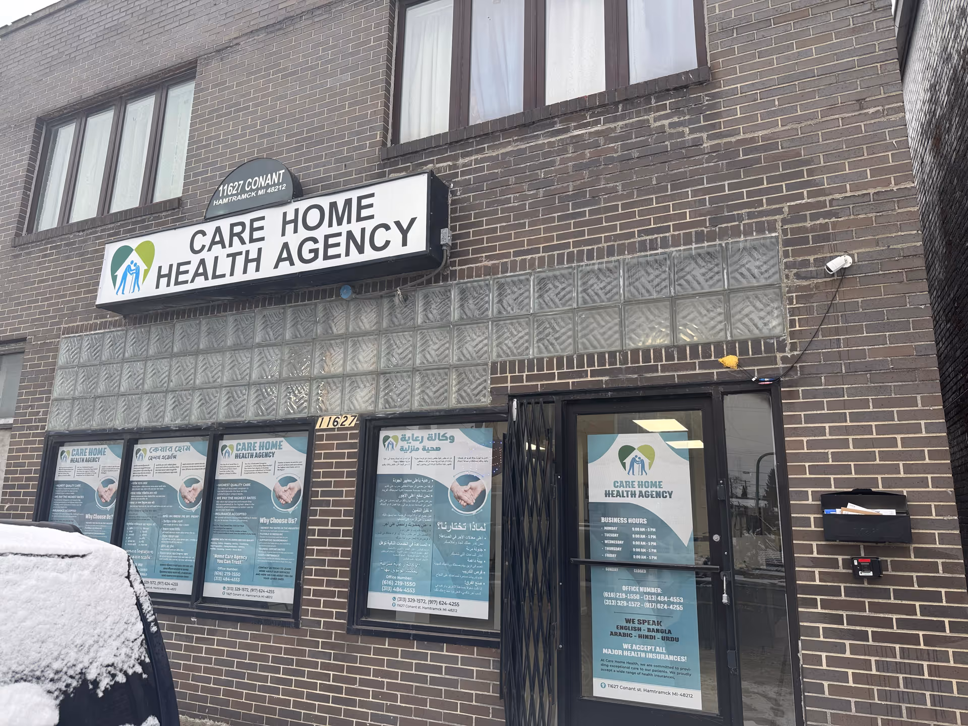 Brick building storefront with CARE HOME HEALTH AGENCY sign and posters in windows.