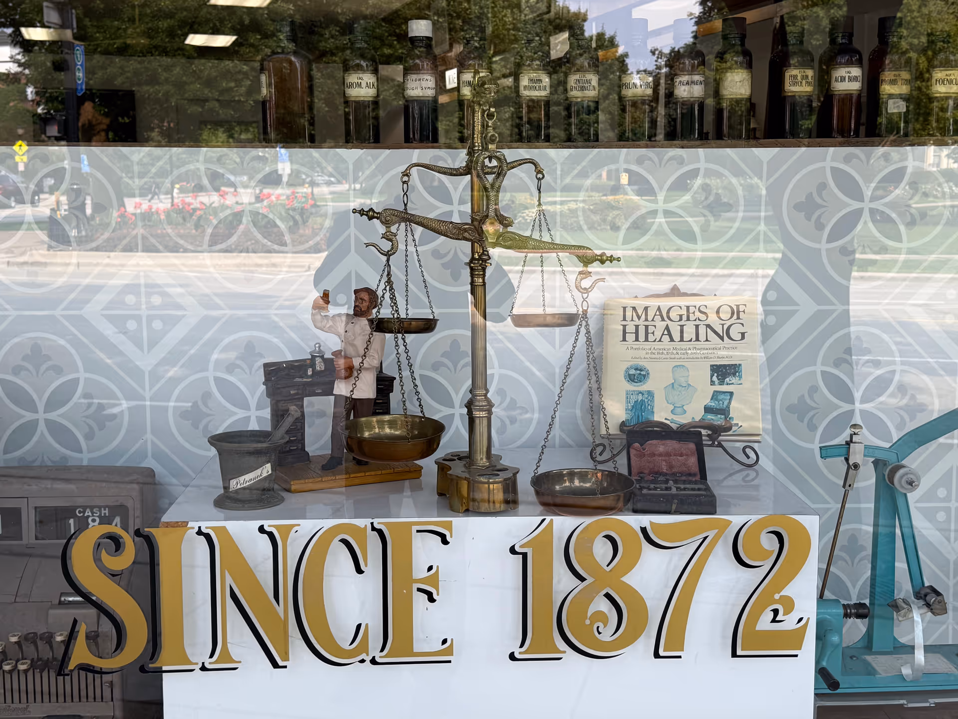 A storefront window display with an antique balance scale and old medical equipment.