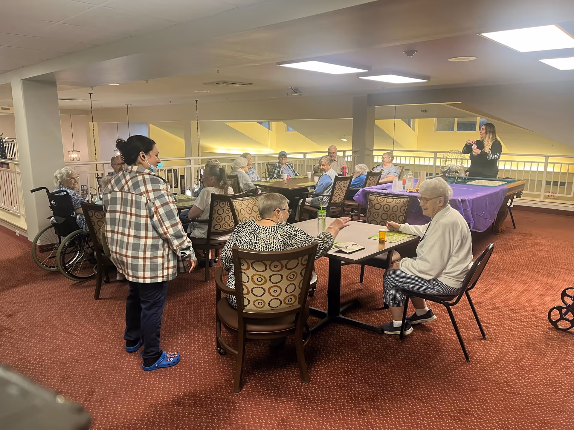 Elderly residents gather at tables in a KHOBCARE facility dining area.