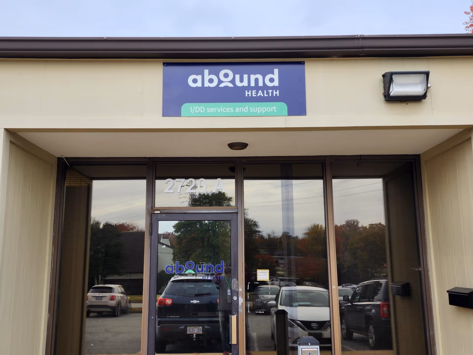 Exterior view of a beige building entrance with an Abound Health sign above the glass doors.