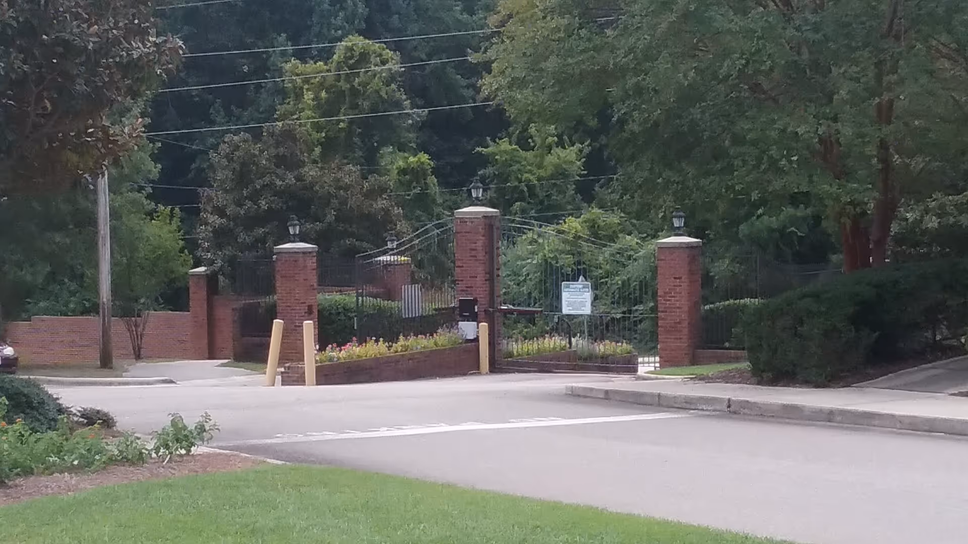Gated entrance with brick pillars and an iron gate at a senior living community.