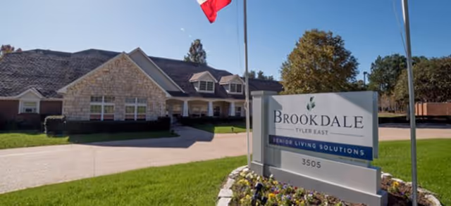 Exterior view of Brookdale Tyler East senior living facility with a sign and landscaping.