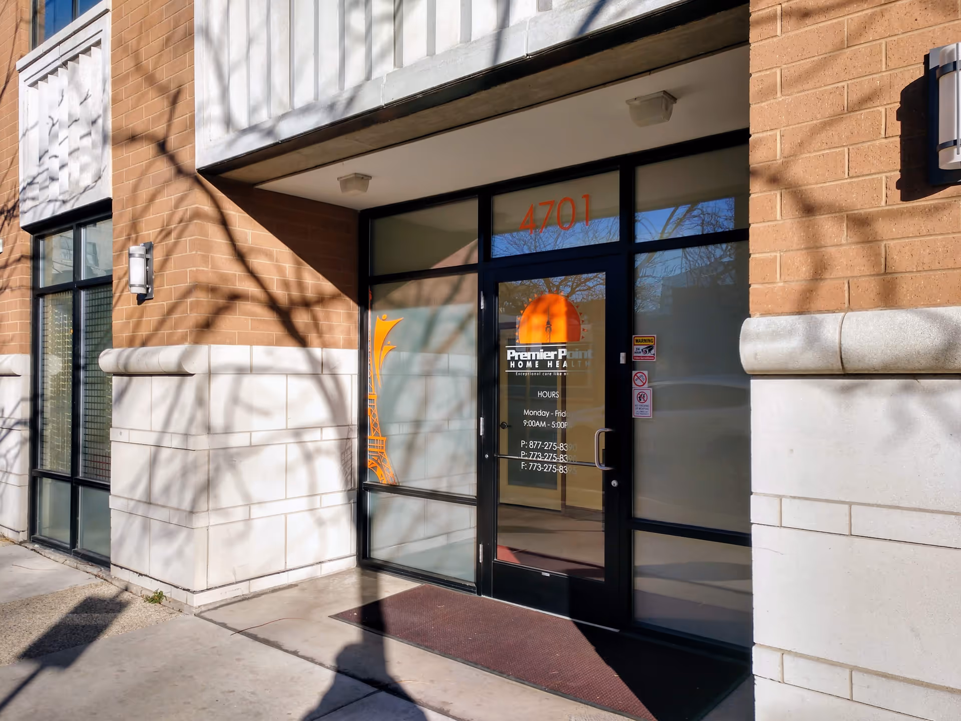 Exterior entrance of Premier Point Home Health with glass doors on brick facade.
