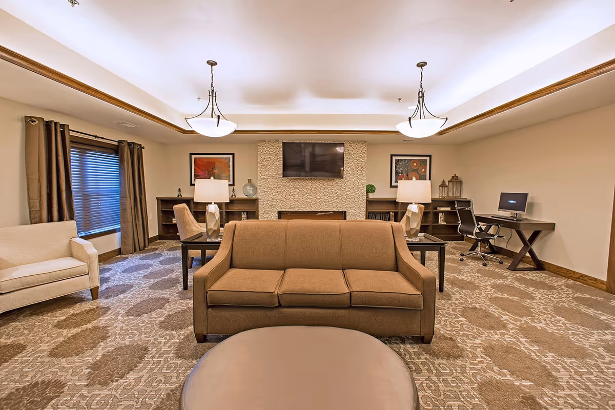 Spacious living room with sofa, chairs, coffee table, computers, and a wall-mounted TV.