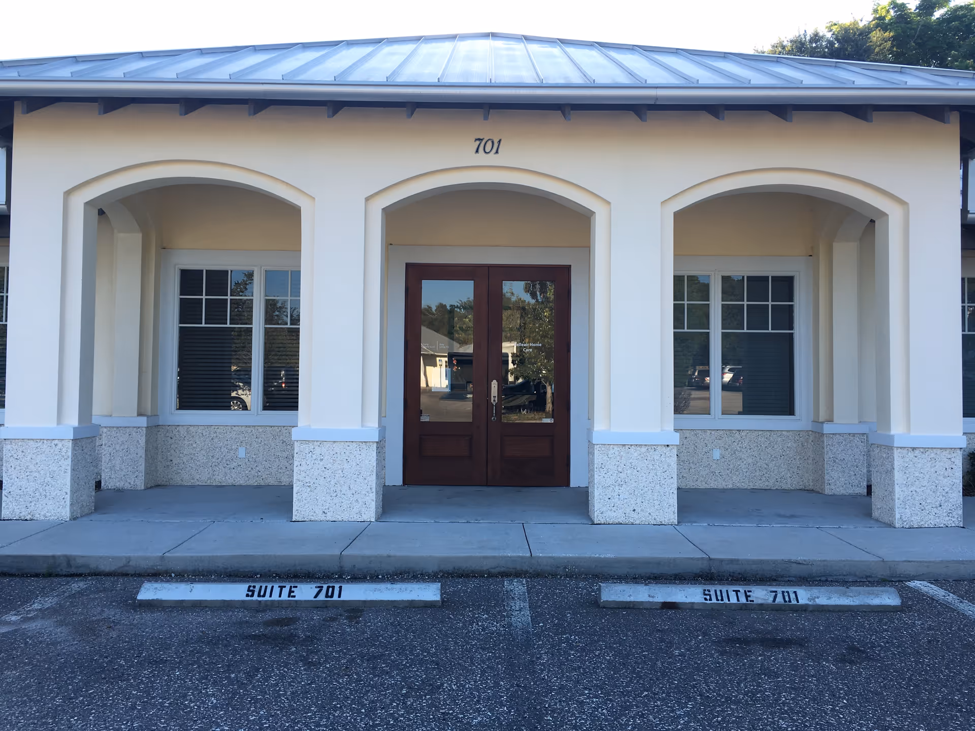 Front view of a beige building entrance with arched doorways, windows, and suite 701.