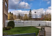 Outdoor courtyard of Achieve Rehab and Nursing Facility with white fence, benches, and trees.
