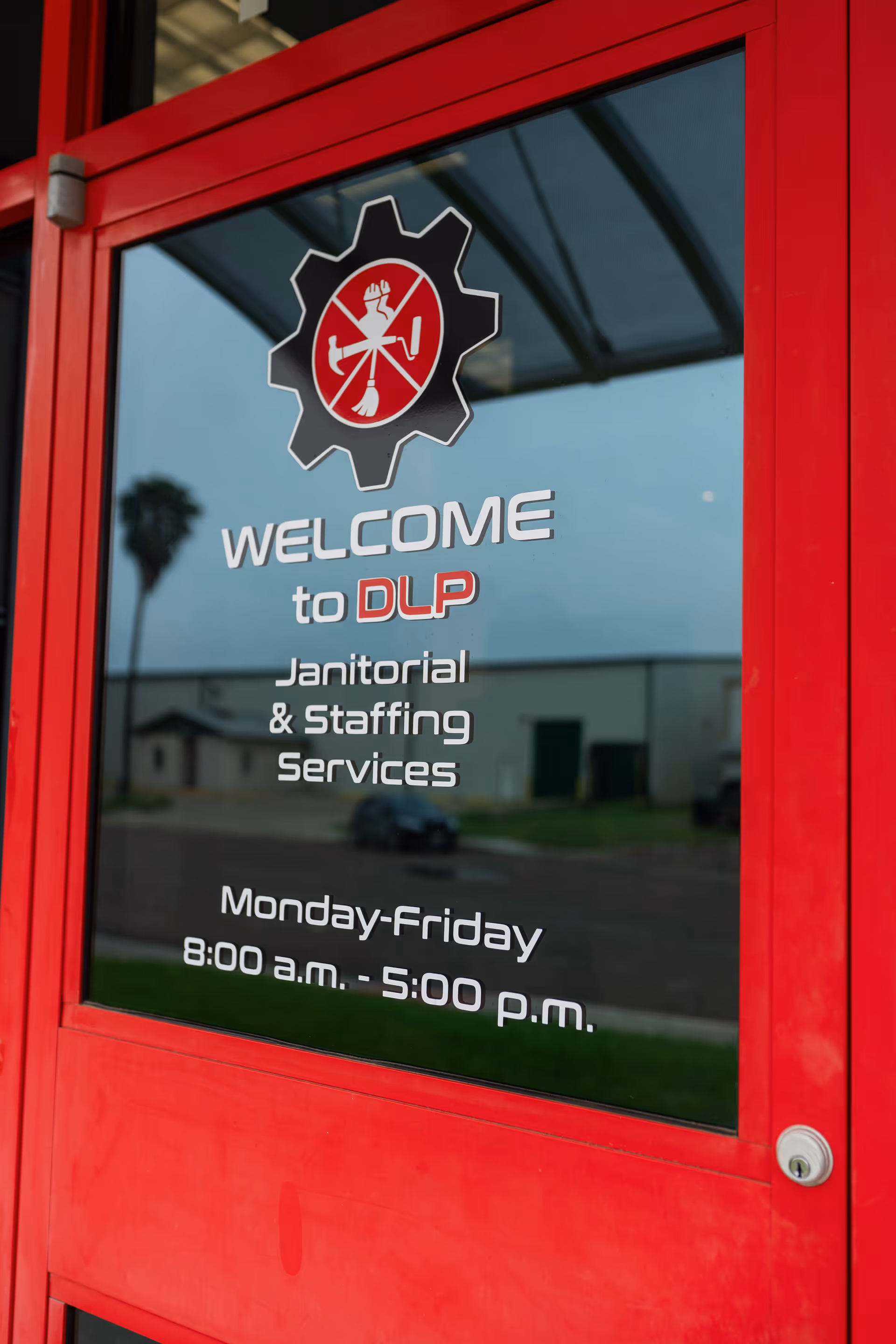 Red door with glass panel displaying 'Welcome to DLP Janitorial & Staffing Services' sign.