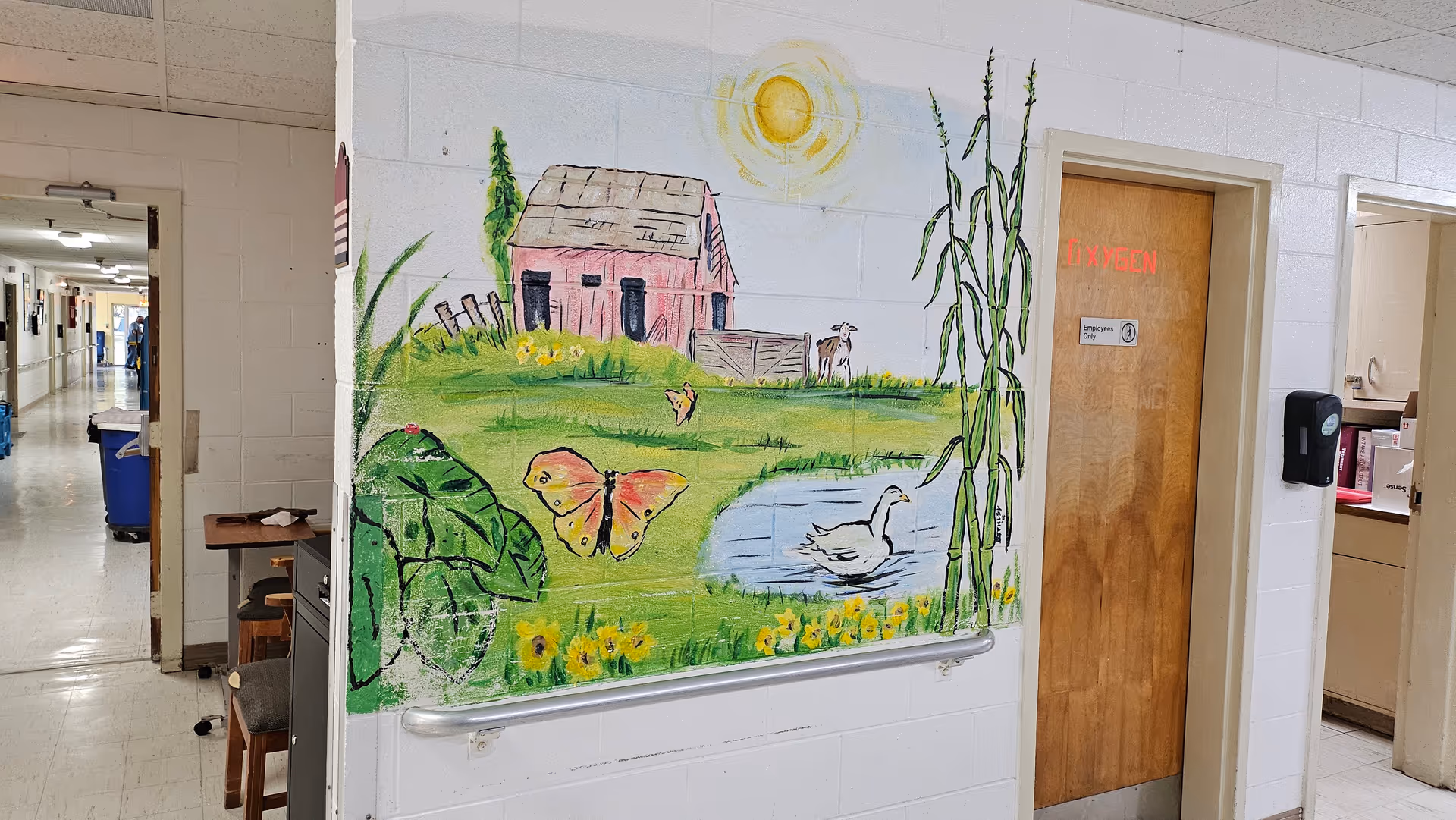 Colorful mural on hallway wall depicts countryside scene with barn, pond, and sun.