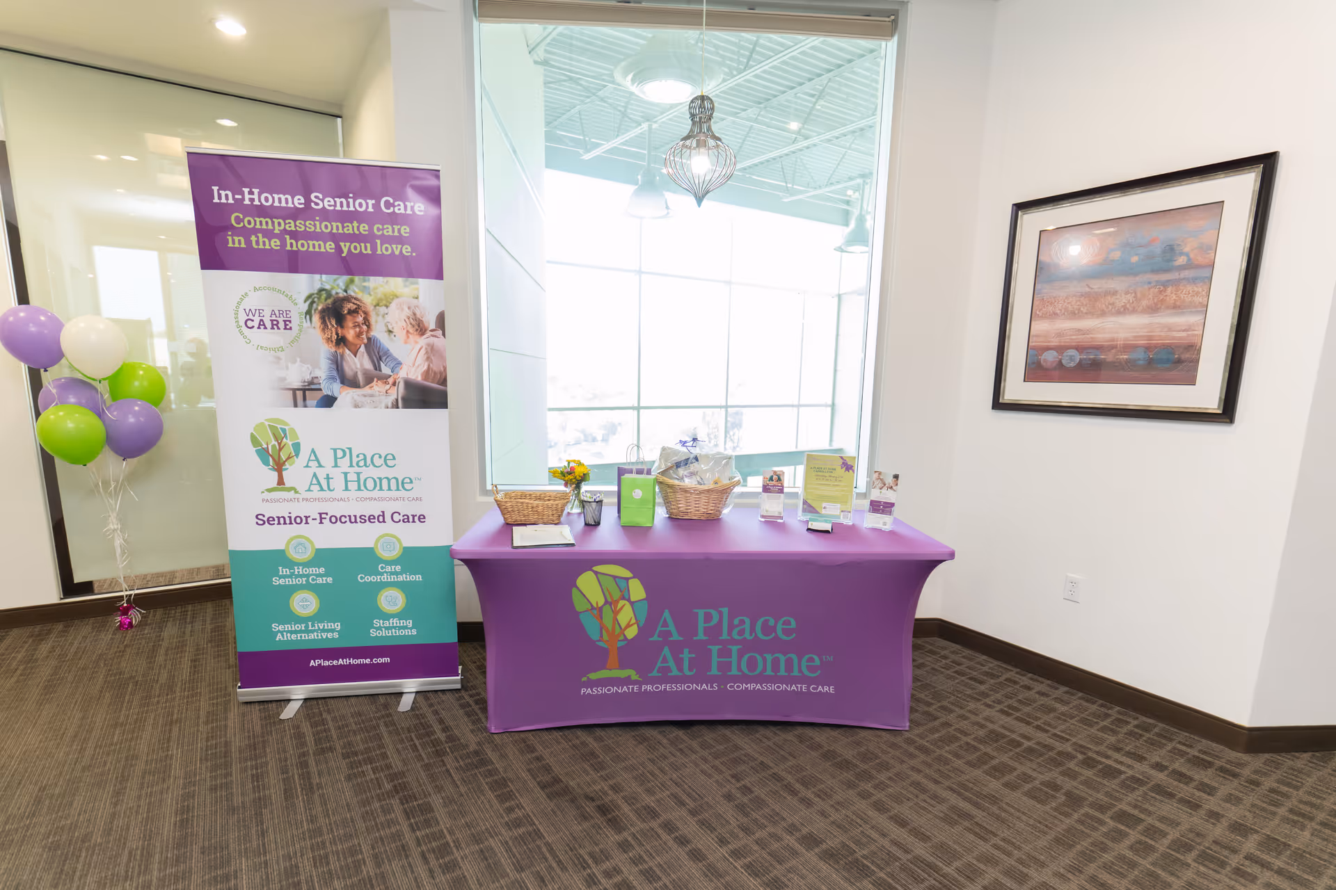 Lobby display table with purple A Place At Home banner and brochures.