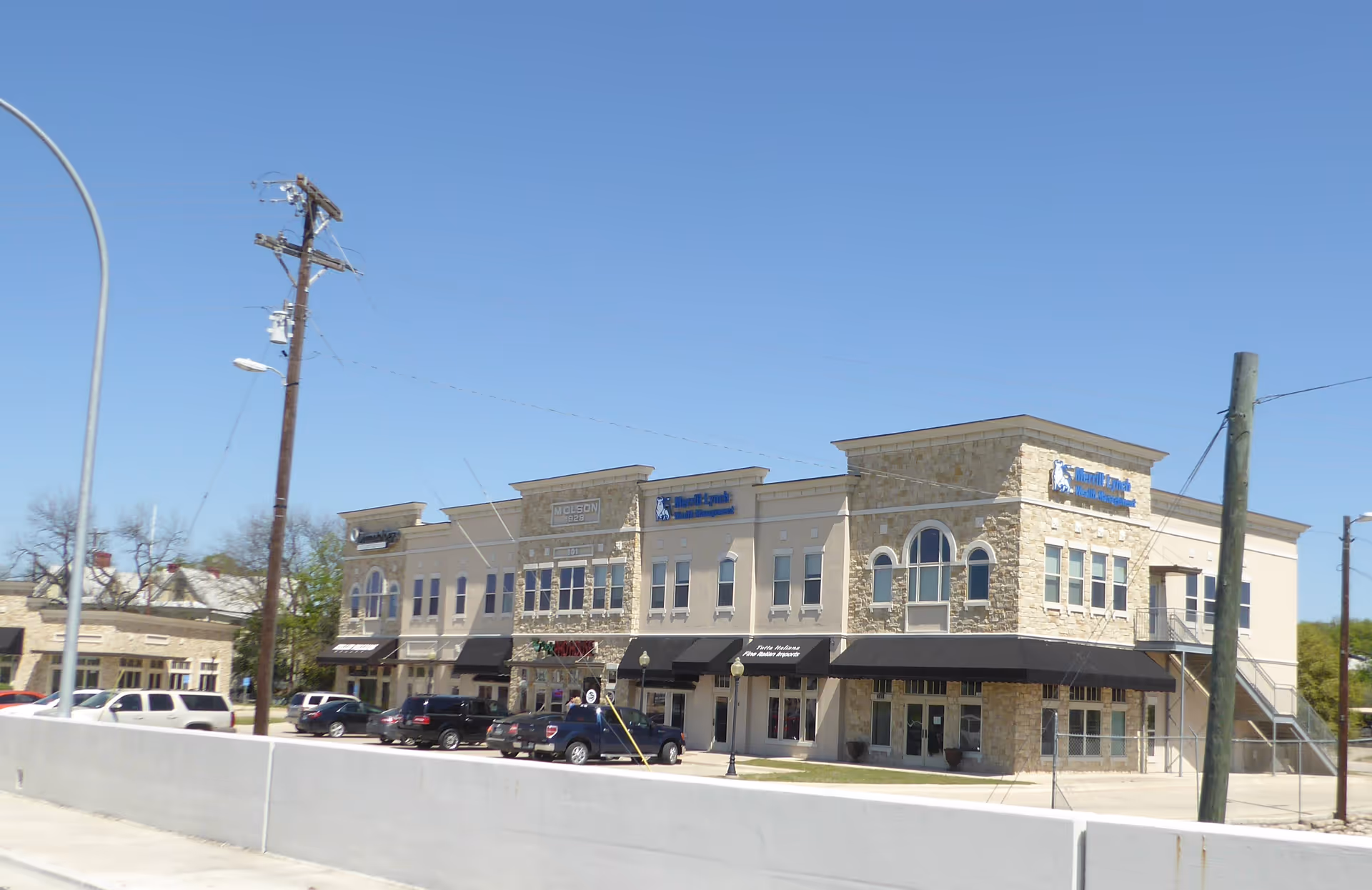 Two-story stone building with Capitol Home Health signage and black awnings along a sunny street.