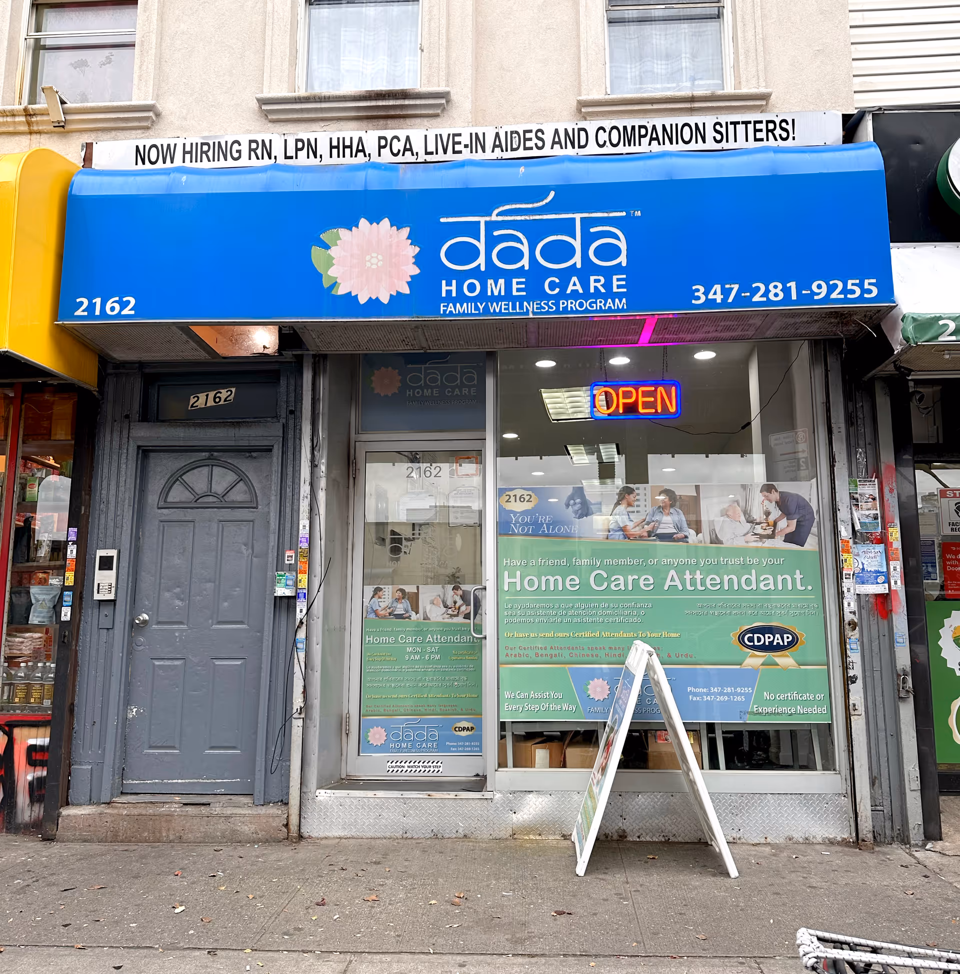 Blue Dada Home Care sign above a glass storefront with an open neon sign.
