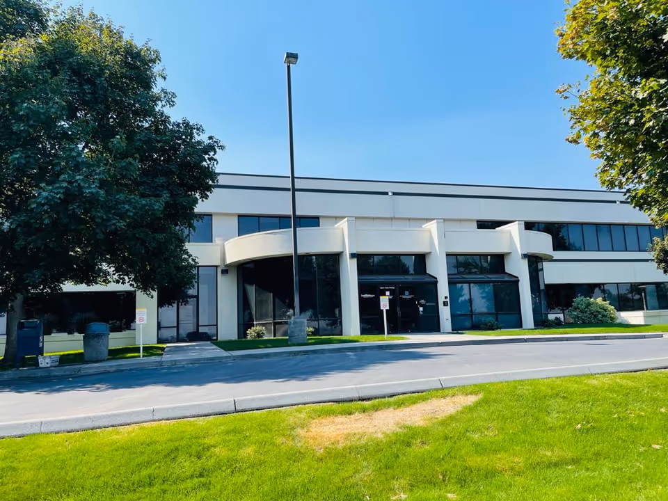Serengeti Care facility exterior with glass doors, curved entry, trees, and a grassy front lawn.