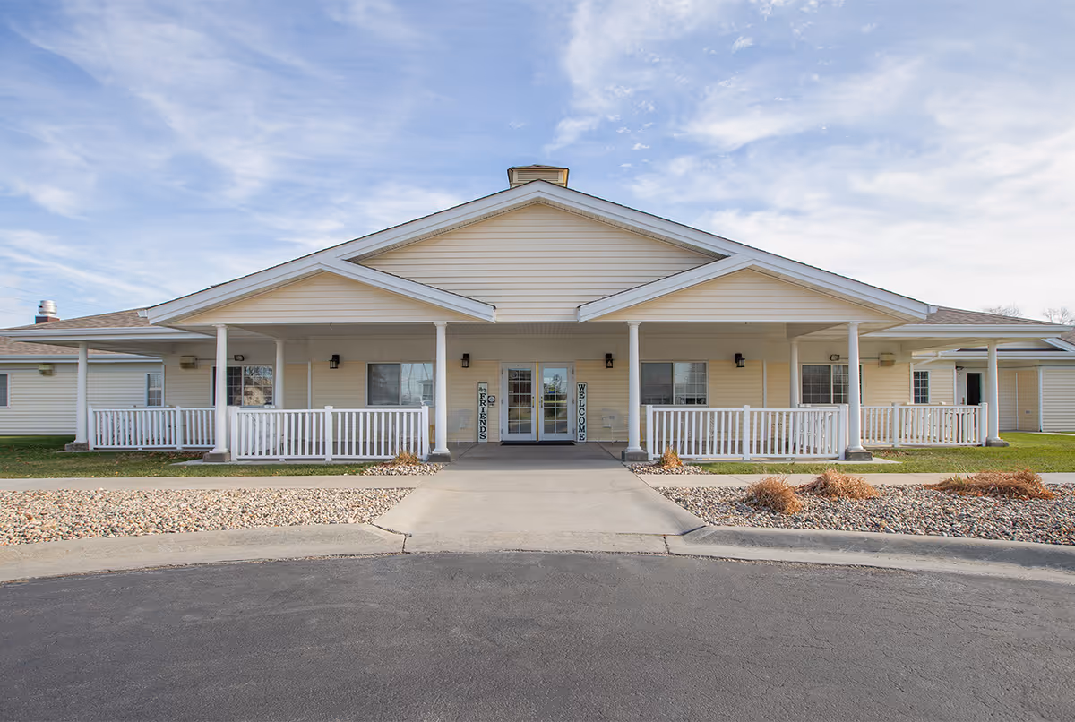 Single story senior living facility with a covered front porch and white railings.