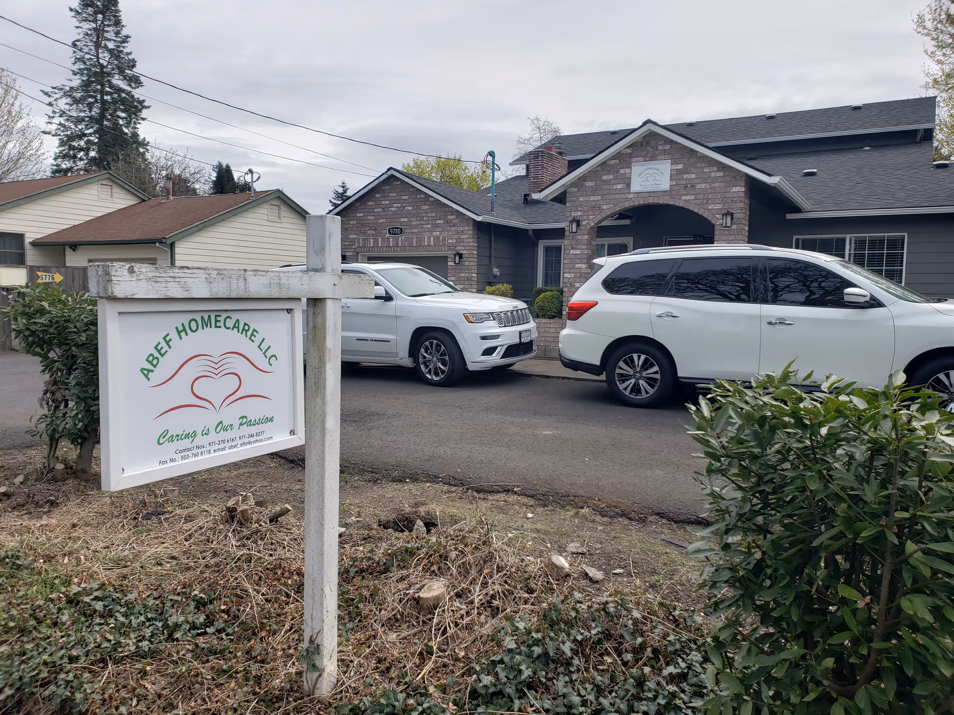 Front view of ABEF Homecare LLC sign with two parked cars in driveway.