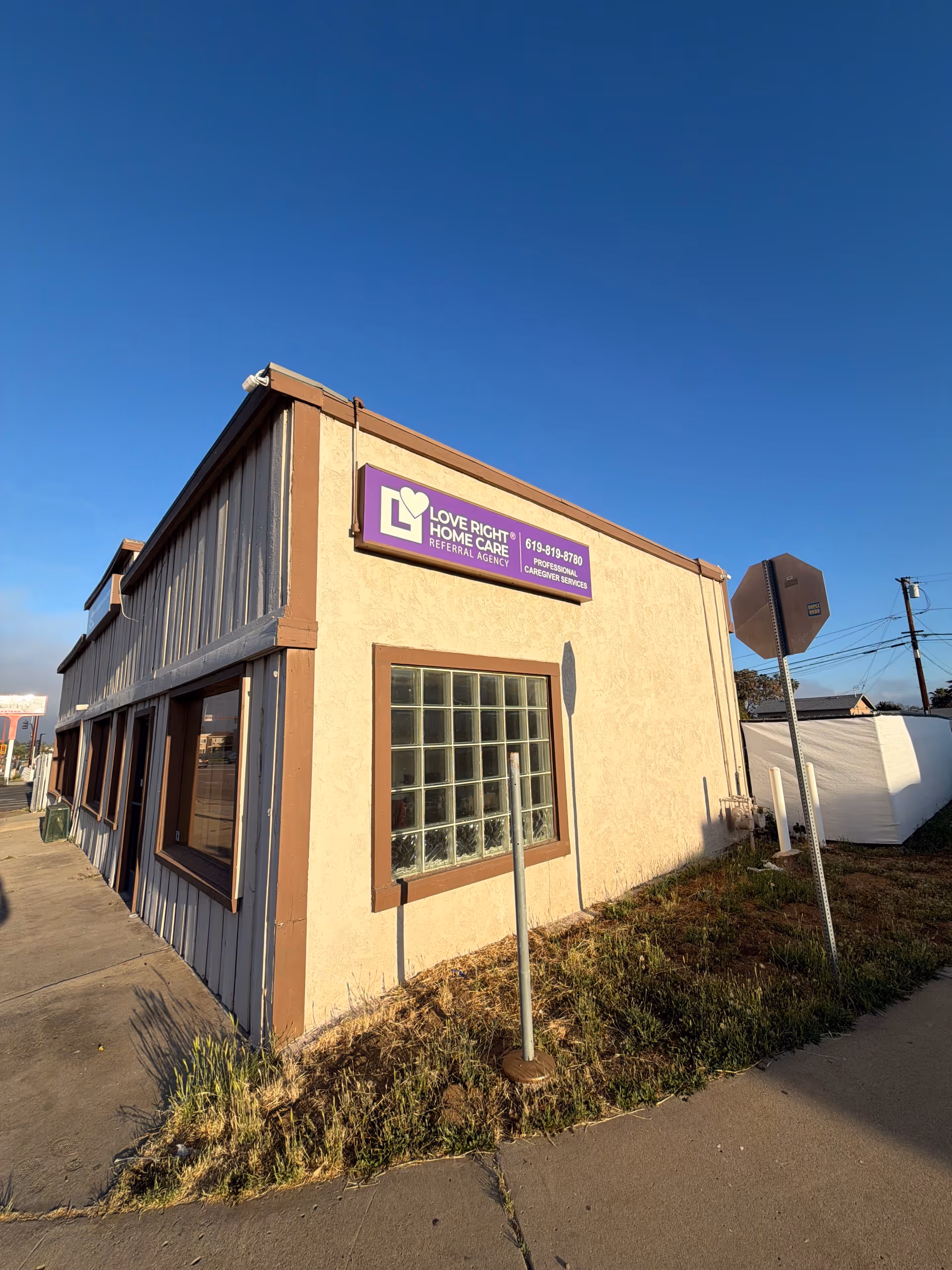 A tan, single-story building with a purple Love Right Home Care sign.