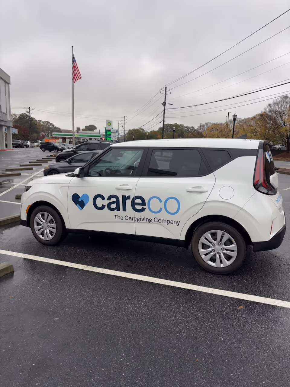 White CareCo vehicle with logo parked in a wet parking lot.