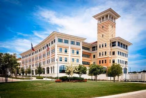 Exterior view of a modern multi-story senior living facility with a tower and manicured lawn.